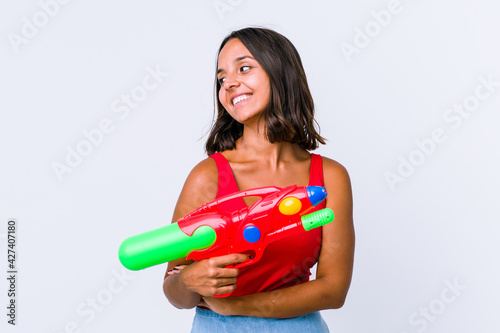 Young mixed race woman holding a water gun isolated smiling confident with crossed arms.