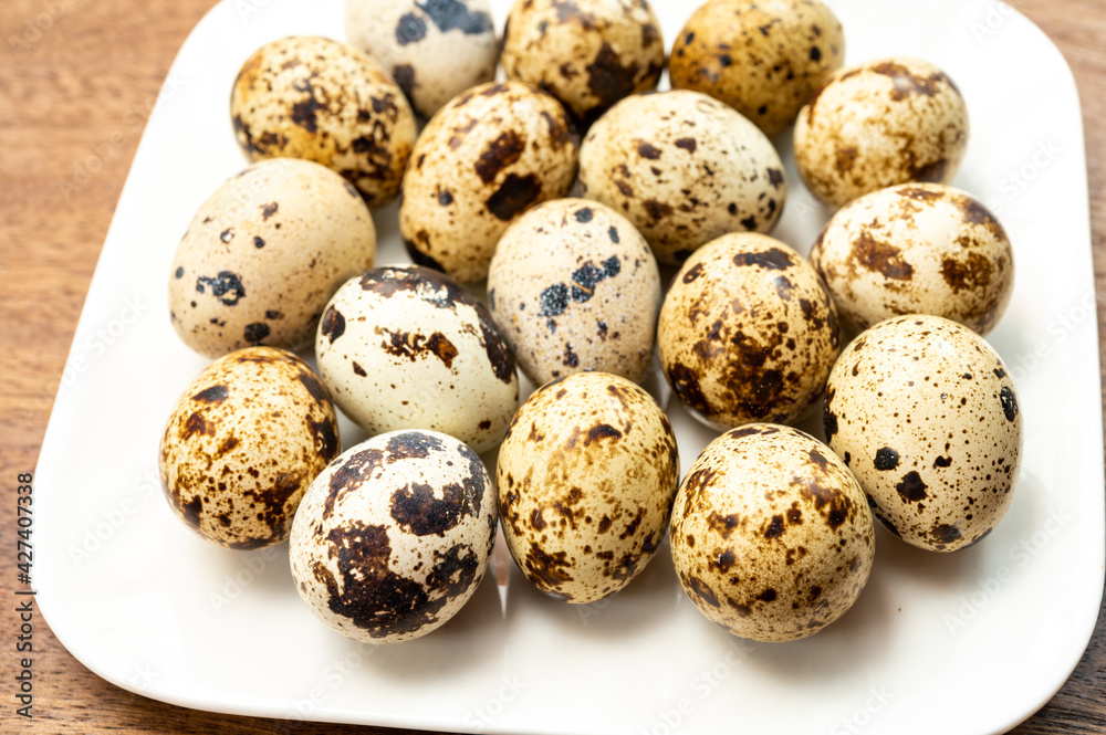 Fresh small spotted partridge eggs on white board