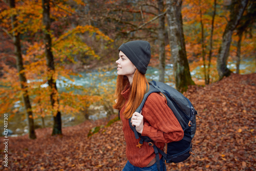 woman hiker walks in the forest in autumn in nature near the river and leaves landscape