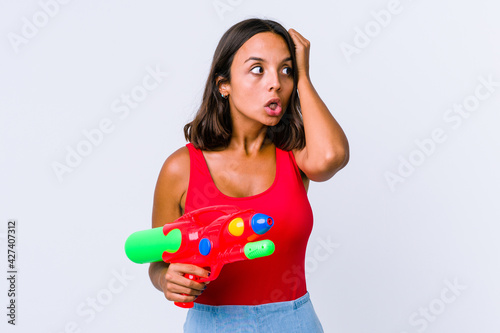 Young mixed race woman holding a water gun isolated being shocked  she has remembered important meeting.