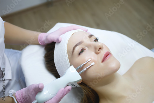 Cosmetologist does microcurrent procedure of a beautiful woman. Women s cosmetology in the beauty salon