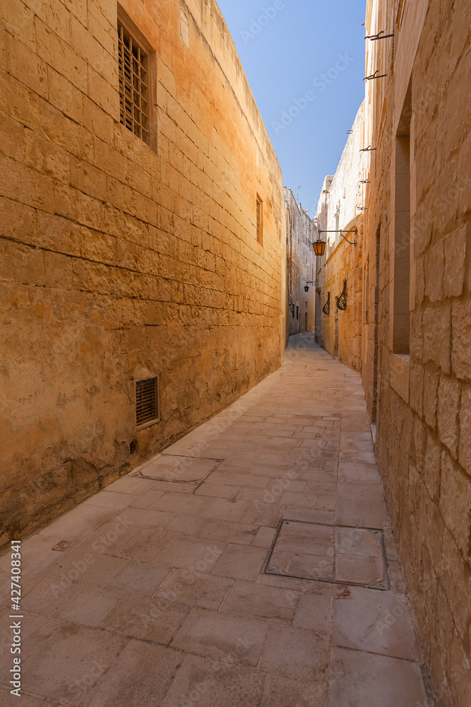 Ancient narrow street in Mdina, Malta. Old buildings with old fashioned lanterns.