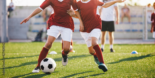Two young football players running ball. Soccer players compete on training game. Football practice drills; attack and defence training unit