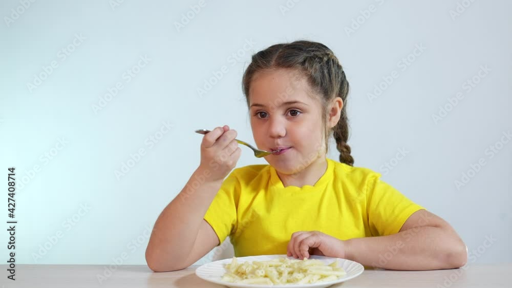 child eating pasta. healthy a food vegetarianism concept. girl child at the table in the kitchen eating pasta. kid eating pasta. little girl at indoor the table eats short spaghetti pasta child eating pasta. healthy a food vegetarianism concept. girl child at the table in the kitchen eating pasta. kid eating pasta. little girl at indoor the table eats short spaghetti pasta