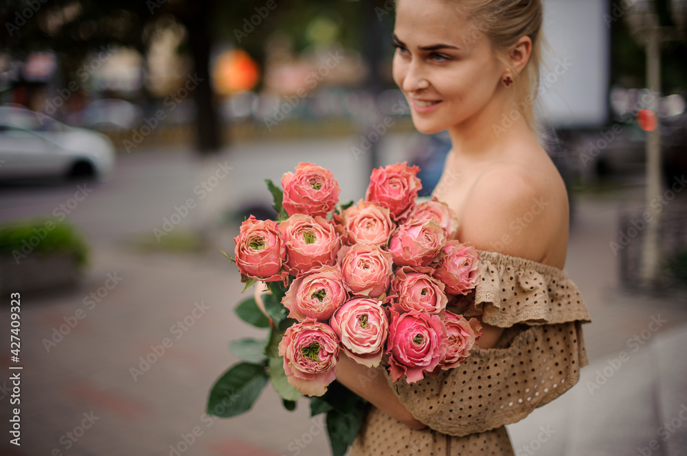 Fototapeta premium excellent view of rosebuds in flower bouquet in the hands of young smiling woman