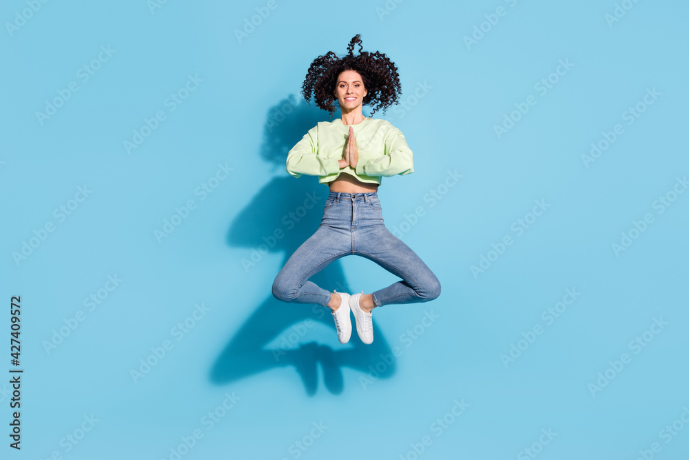Full size portrait of cheerful energetic girl jumping hands palms pleading isolated on blue color background