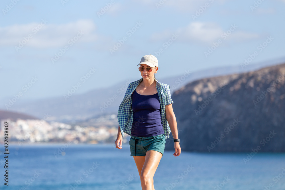 Young slim woman enjoying walking along coastline