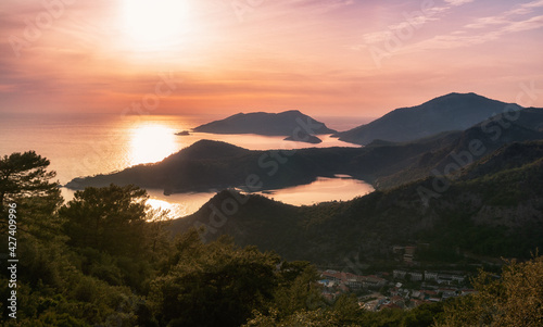 Amazing aerial view of beautiful sunset Blue Lagoon in Oludeniz, Turkey. Summer landscape with beach and mountains, green forest, azure water, sandy beach and blue sky in bright sunny day best tourist
