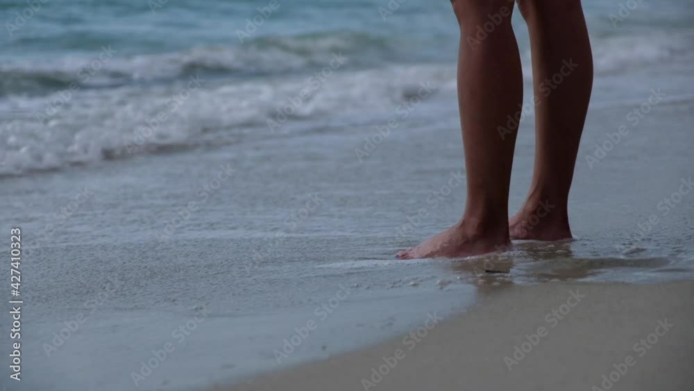 Slow motion of the sea wave hitting legs while a woman standing on the white beach Slow motion of the sea wave hitting legs while a woman standing on the white beach