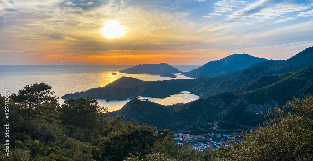 Amazing aerial view of beautiful sunset Blue Lagoon in Oludeniz, Turkey. Summer landscape with beach and mountains, green forest, azure water, sandy beach and blue sky in bright sunny day best tourist