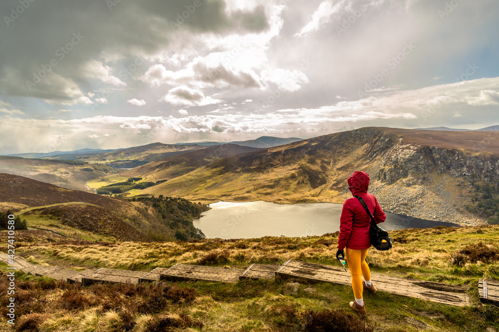 woman from behind on wooden path looking towards Lough Tay in the wicklow mountains Ireland woman from behind on wooden path looking towards Lough Tay in the wicklow mountains Ireland