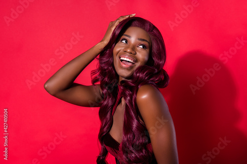 Photo of attractive nice afro american young woman look empty space hold hand empty space isolated on red color background