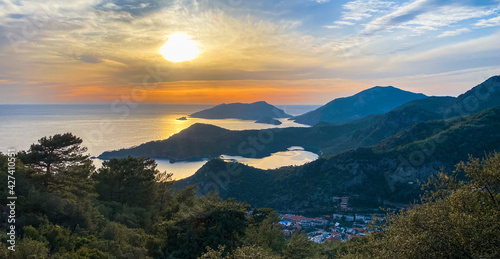 Amazing aerial view of beautiful sunset Blue Lagoon in Oludeniz  Turkey. Summer landscape with beach and mountains  green forest  azure water  sandy beach and blue sky in bright sunny day best tourist