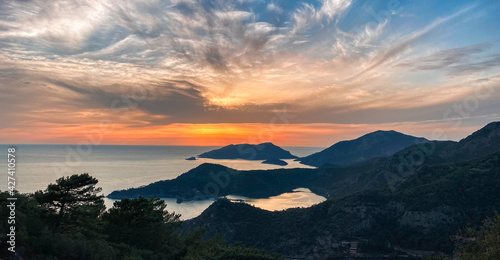 Amazing aerial view of beautiful sunset Blue Lagoon in Oludeniz, Turkey. Summer landscape with beach and mountains, green forest, azure water, sandy beach and blue sky in bright sunny day best tourist