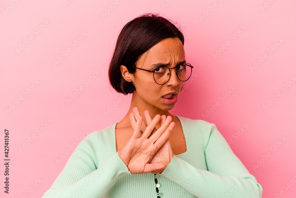 Young mixed race woman isolated on pink background doing a denial gesture