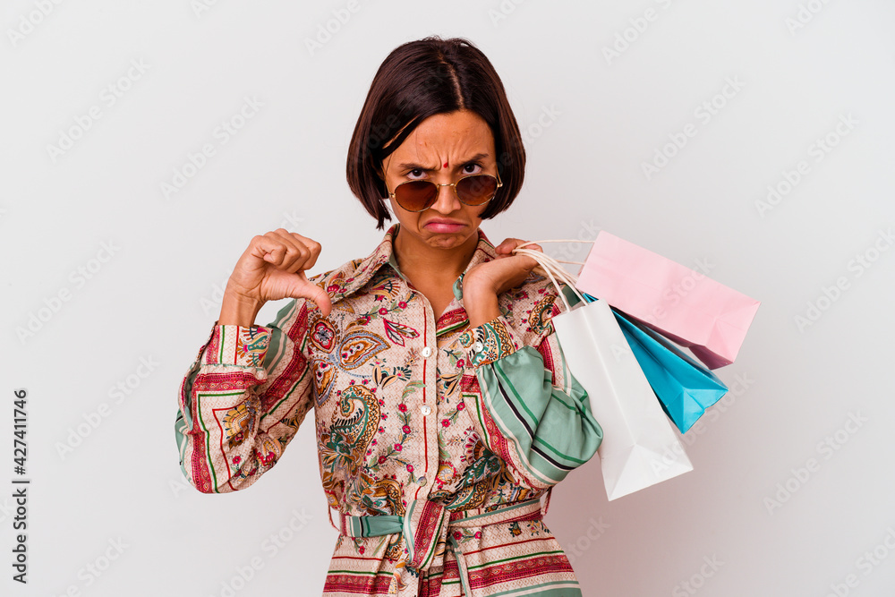 Young Indian woman shopping some clothes isolated on white background showing a dislike gesture, thumbs down. Disagreement concept. Young Indian woman shopping some clothes isolated on white background showing a dislike gesture, thumbs down. Disagreement concept.