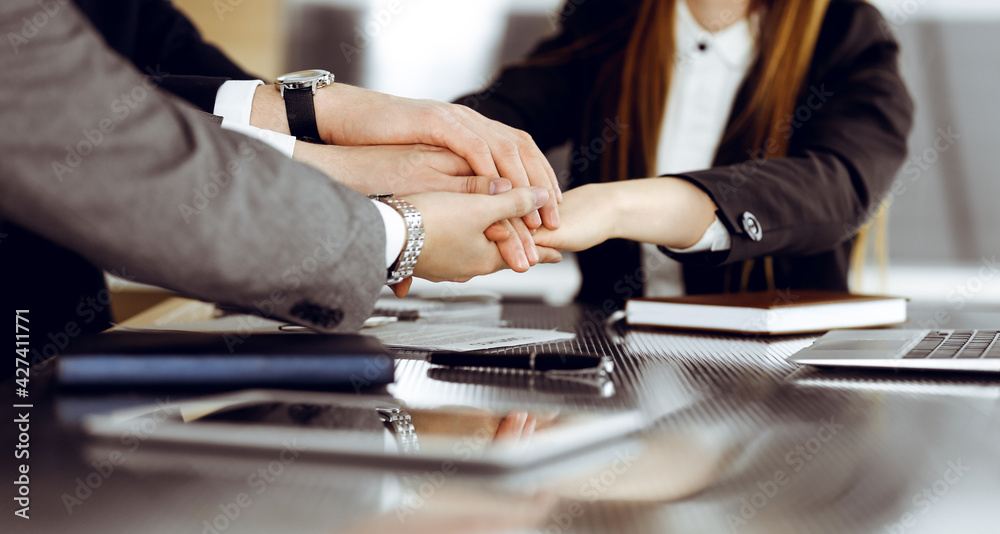 Unknown business people group joining hands in modern office. Businessmen and women making circle with their hands as a team, close-up