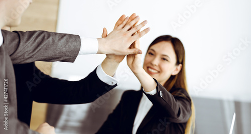 Fototapeta Naklejka Na Ścianę i Meble -  Unknown business people group joining hands in modern office. Businessmen and women making circle with their hands as a team, close-up