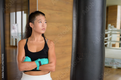 Asian woman kick boxer ready for exercise at gym and thinking © Ranta Images
