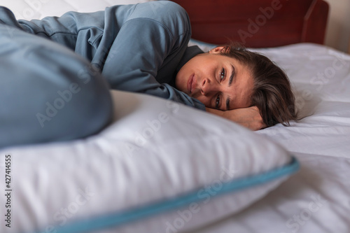 Woman lying in bed curled up in pain
