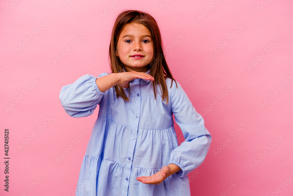 Little caucasian girl isolated on pink background holding something with both hands, product presentation. Little caucasian girl isolated on pink background holding something with both hands, product presentation.