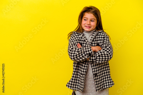 Little caucasian girl isolated on yellow background smiling confident with crossed arms.