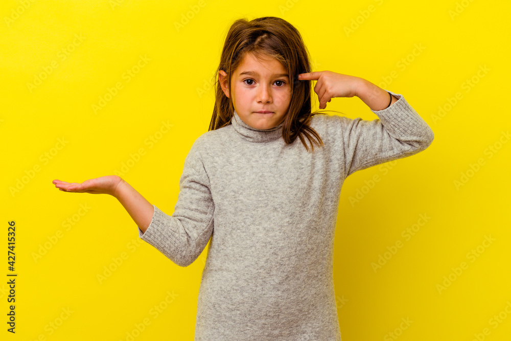 Little caucasian girl isolated on yellow background holding and showing a product on hand. Little caucasian girl isolated on yellow background holding and showing a product on hand.