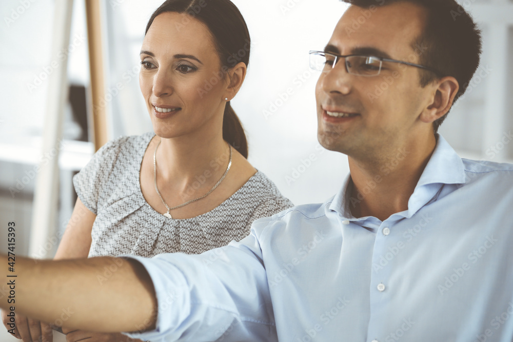 Businessman and hispanic business woman working with computer in a modern office. Group of diverse people. Teamwork, partnership and business concept Businessman and hispanic business woman working with computer in a modern office. Group of diverse people. Teamwork, partnership and business concept