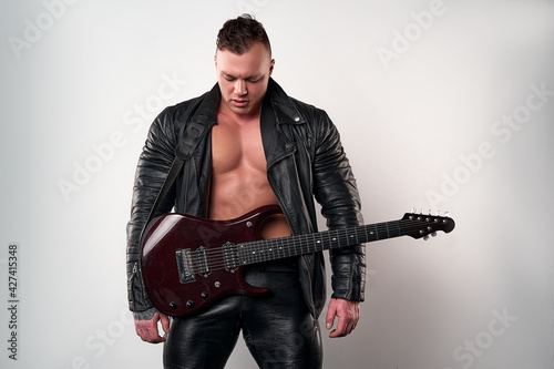 brutal man in leather jacket poses with a guitar on a white background                      