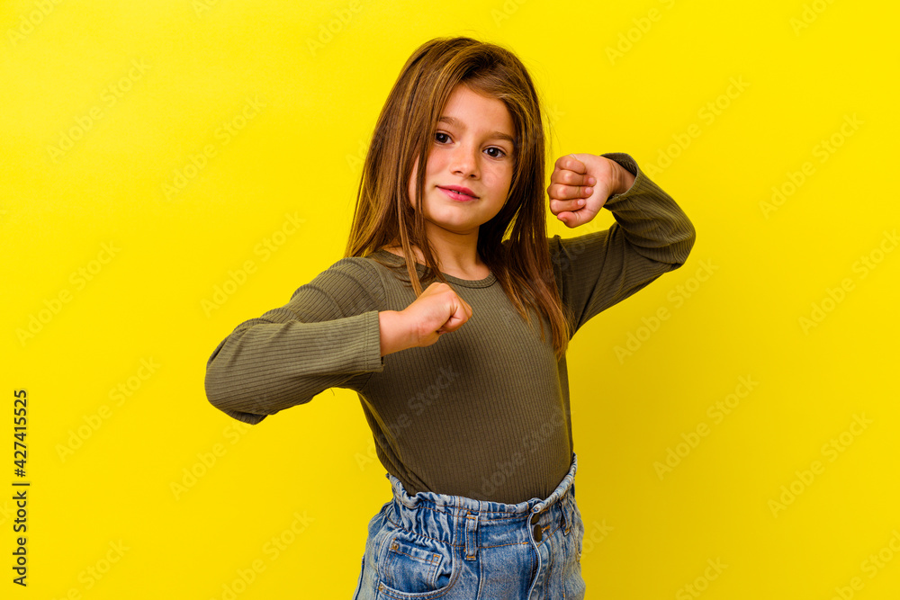 Little caucasian girl isolated on yellow background throwing a punch, anger, fighting due to an argument, boxing. Little caucasian girl isolated on yellow background throwing a punch, anger, fighting due to an argument, boxing.