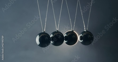Balls in Newton's pendulum hit each other in the light of the spotlight beam