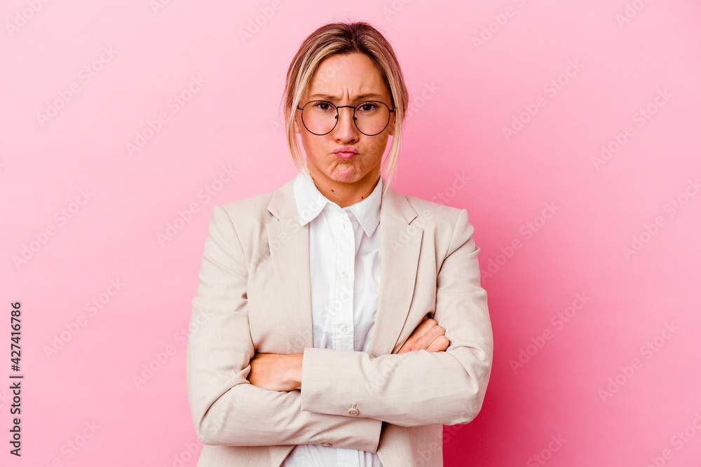 Young caucasian mixed race business woman isolated on pink background blows cheeks, has tired expression. Facial expression concept.