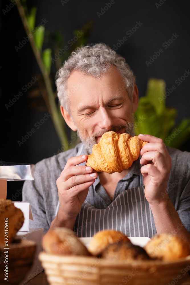 Man with closed eyes inhaling smell of croissant Man with closed eyes inhaling smell of croissant