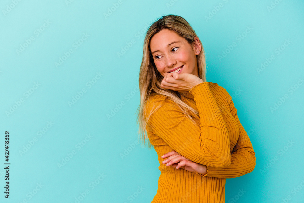 Young mixed race woman isolated on blue background relaxed thinking about something looking at a copy space. Young mixed race woman isolated on blue background relaxed thinking about something looking at a copy space.