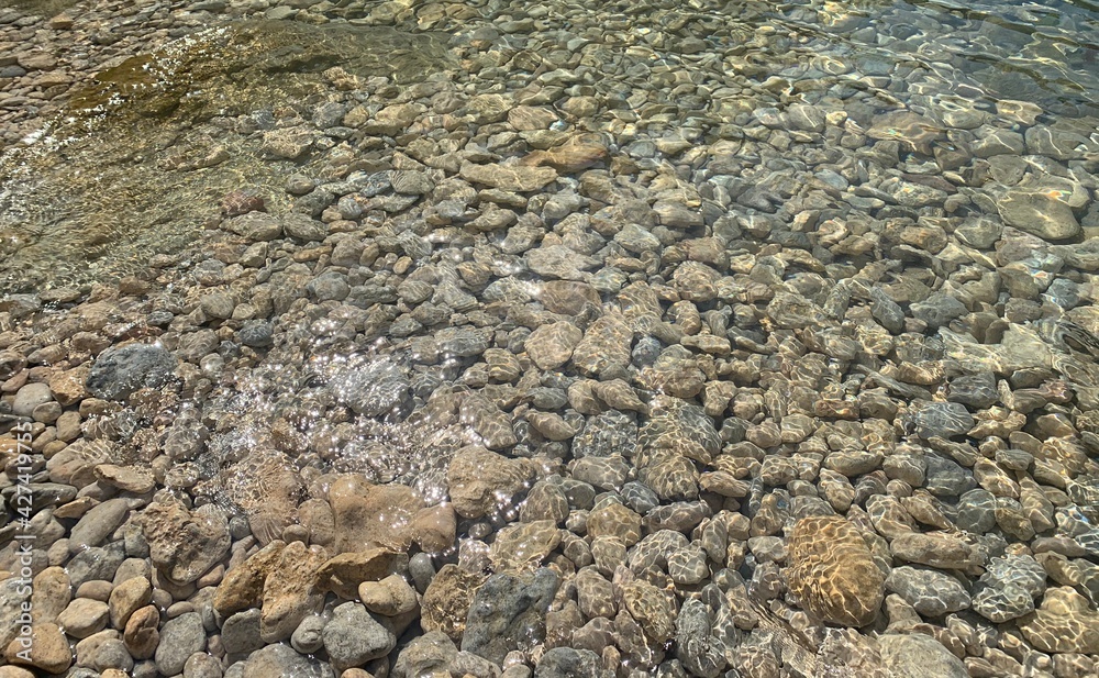 Sea transparent water, crystal clear sea water surface on pebbles beach. Zen landscape, mediation of nature, beautiful seascape, sunlight on stones. Sea transparent water, crystal clear sea water surface on pebbles beach. Zen landscape, mediation of nature, beautiful seascape, sunlight on stones.