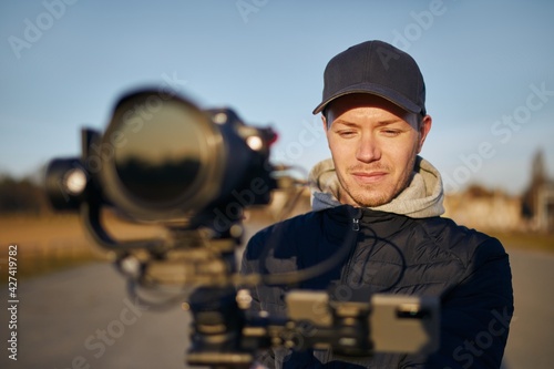 Content creator during filming with camera and gimbal. Portrait of videographer at sunny day.