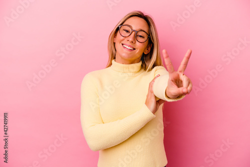 Young mixed race woman isolated on pink background showing victory sign and smiling broadly.
