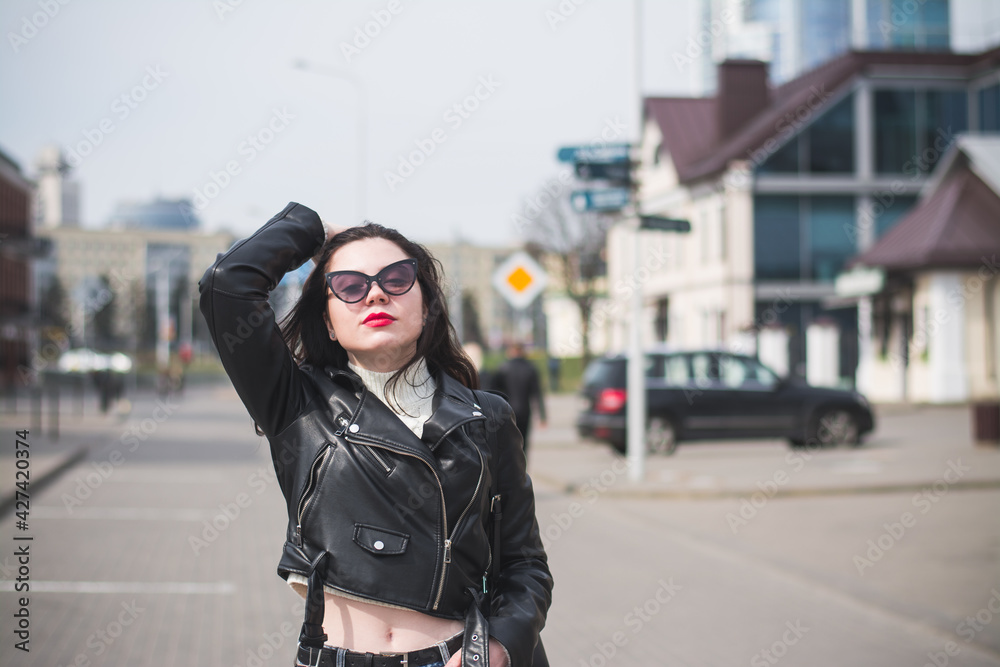 Obraz premium A beautiful hipster girl with a phone in her hands walks down the street