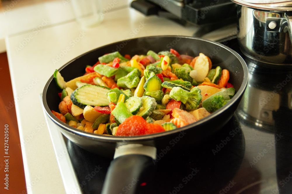 Frozen vegetables in a pan on an induction hob Frozen vegetables in a pan on an induction hob