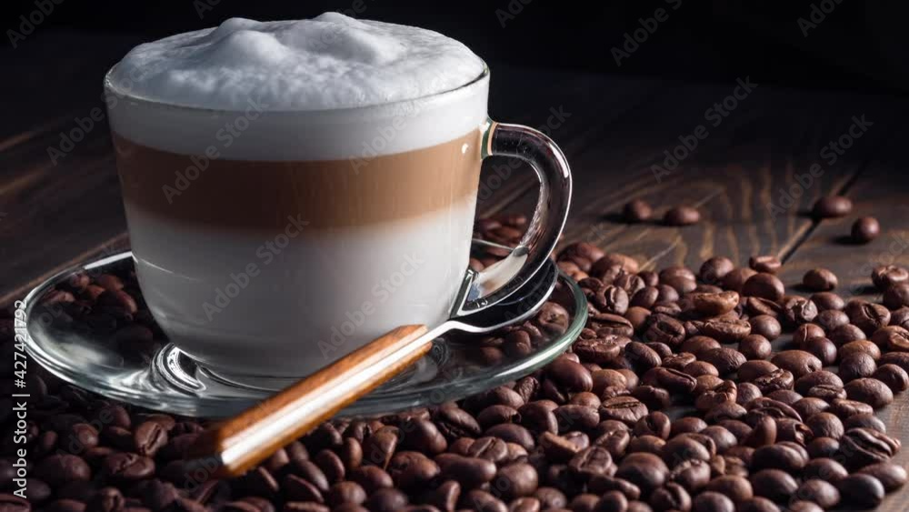 Cup with hot cappuccino drink on roasted coffee beans. dolly shot