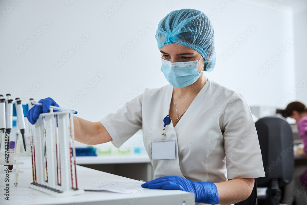 Biochemist analyzing the blood samples in the calibrated serological pipettes Biochemist analyzing the blood samples in the calibrated serological pipettes