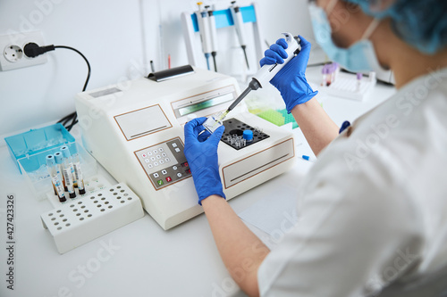 Medical lab technician drawing off liquid from a reagent bottle