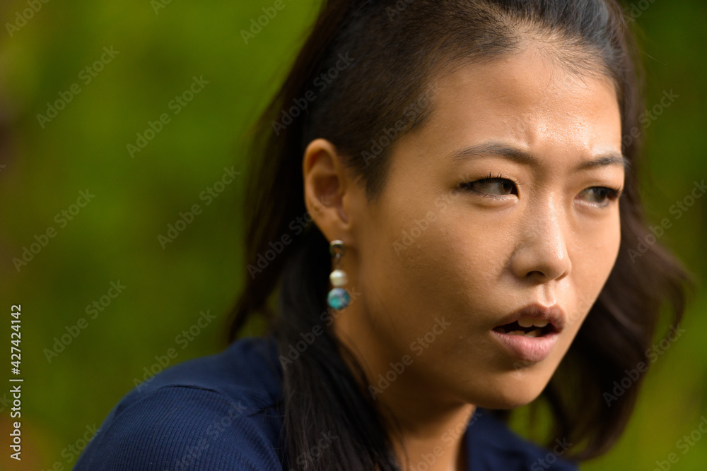 Close-up portrait of beautiful rebel Asian woman face outdoors Close-up portrait of beautiful rebel Asian woman face outdoors
