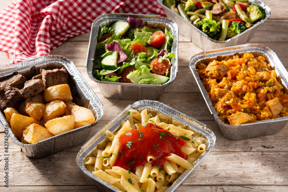 Take away healthy food in foil boxes on wooden table. Take away healthy food in foil boxes on wooden table.
