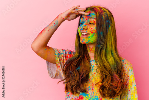 Young Indian woman celebrating holy festival isolated on white background looking far away keeping hand on forehead.