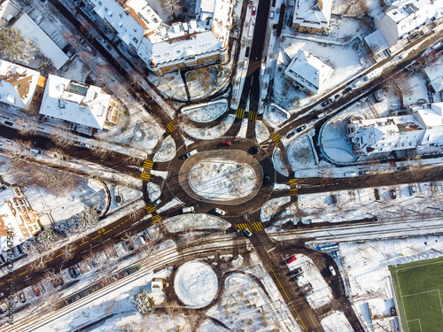 Aerial top down drone shot of  an automotive snow covered roundabout crossroad of many streets crossing in the city of Basel, Switzerland at winter