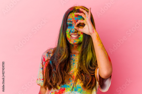 Young Indian woman celebrating holy festival isolated on white background excited keeping ok gesture on eye.