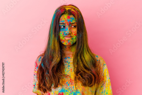 Young Indian woman celebrating holy festival isolated on white background confused, feels doubtful and unsure.