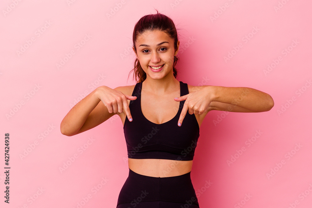 Young sport Indian woman isolated on pink background points down with fingers, positive feeling.