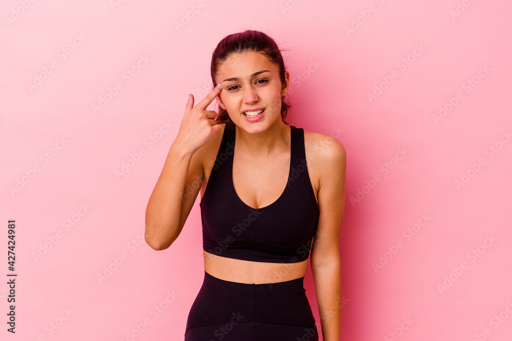 Young sport Indian woman isolated on pink background showing a disappointment gesture with forefinger.